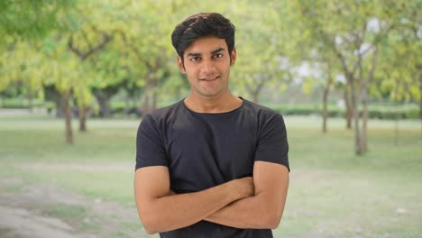 Happy-Indian-man-standing-crossed-hands-in-park