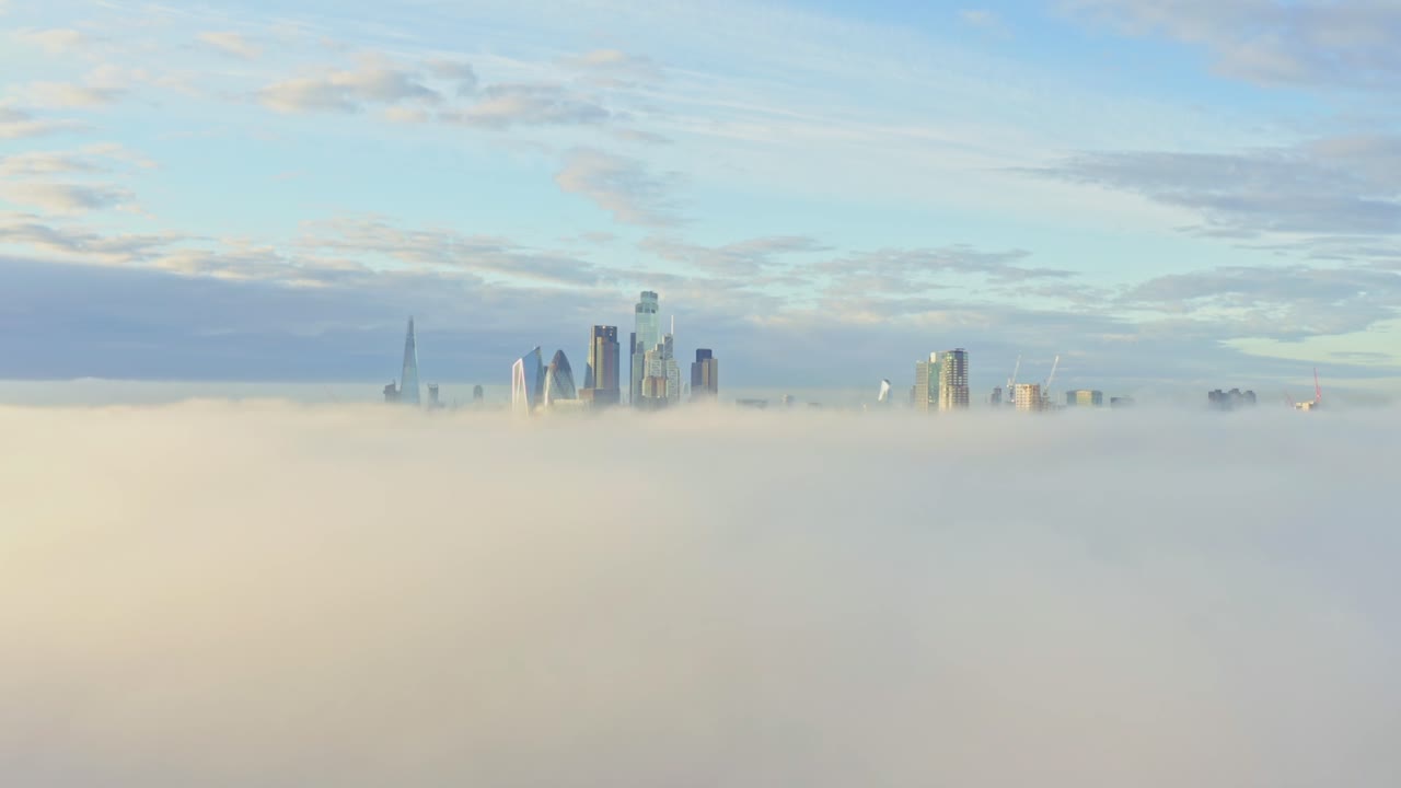 toma aérea sobre la niebla matutina hacia el amanecer de los rascacielos del centro de la ciudad de londres.