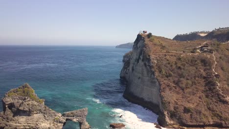 Aerial-view-of-Atuh-beach-on-Nusa-Penida,-Indonesia-on-a-sunny-day-and-with-crystal-blue-water-hitting-the-rock-formations