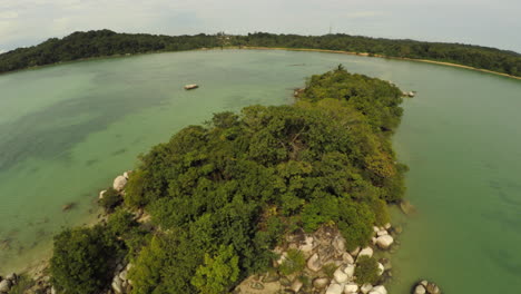 antena de una pequeña isla tropical con arena blanca, con grandes rocas y jungla