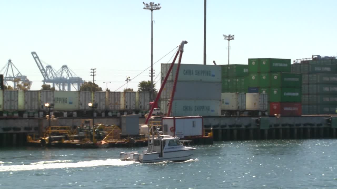 un barco del puerto pasa junto al puerto de long beach y los contenedores de envío