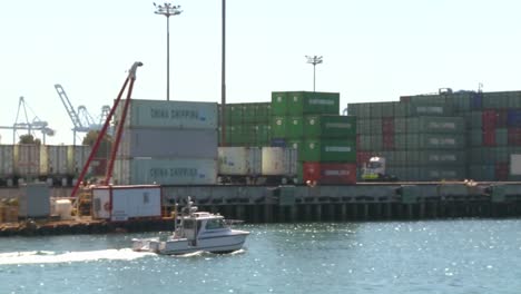 a harbor boat passes beside long beach harbor and shipping containers