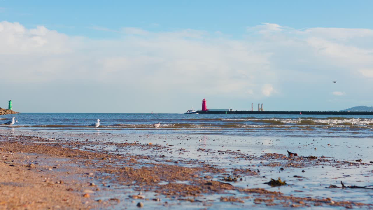 Tranquille acque costiere al faro di Poolbeg con una barca in lontananza