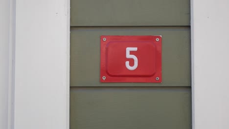 red sign with number 5 on a green wall