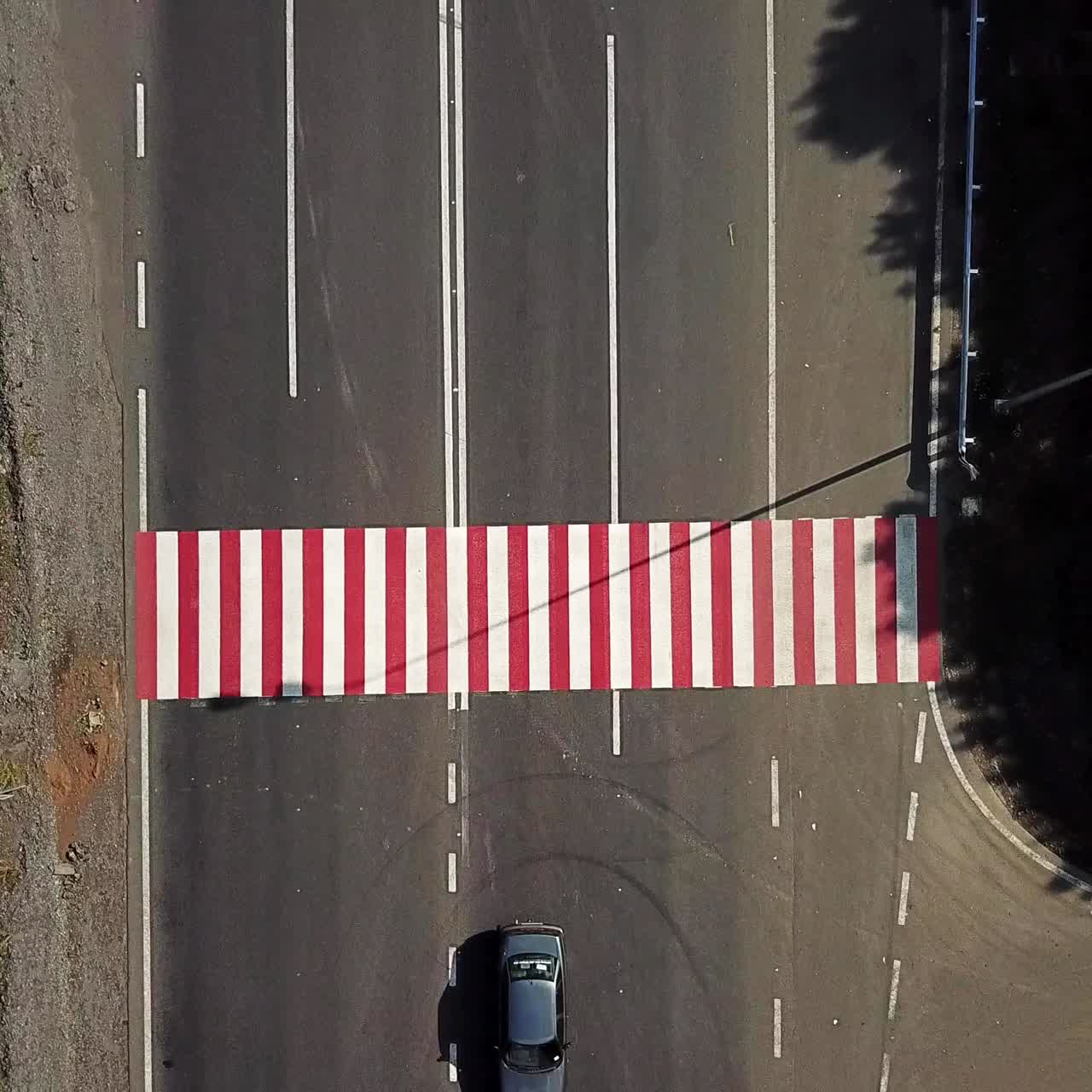 cars are quickly passing a pedestrian crossing in the street of city. Fast traffic cars. Camera motion to up. Aerial view