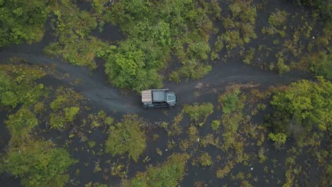 drone aerial bird's-eye view of cars driving off-road over volcanic sand in a forest during camping trip to pacaya volcano, guatemala