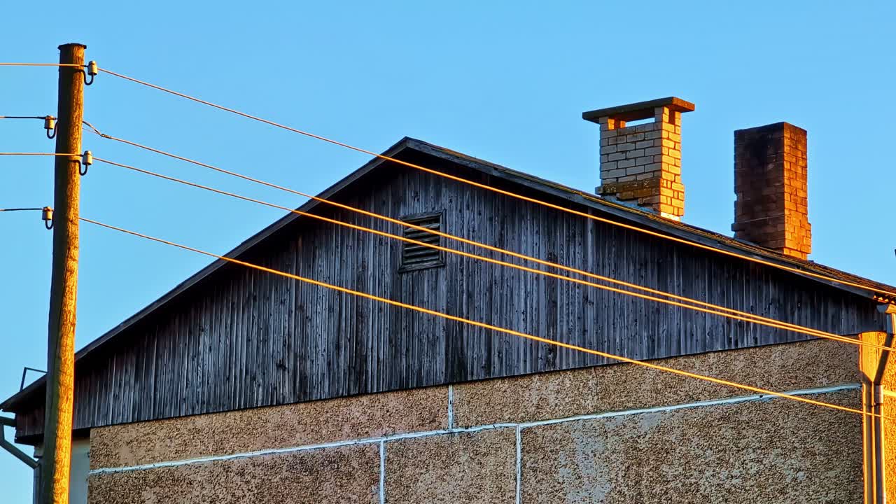 Old House Wall With Power Lines And Brick Chimneys In Golden Hour Light