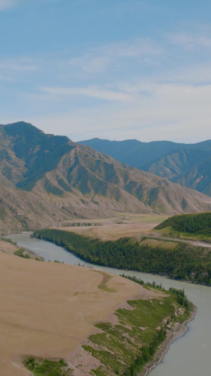 Drohnenaufnahmen eines sich schlängelnden Flusses und eines weiten Tals mit Bergkämmen nahe dem Tschujatrak, Republik Altai, Russland, Sommerlandschaft mit klarem blauem Himmel