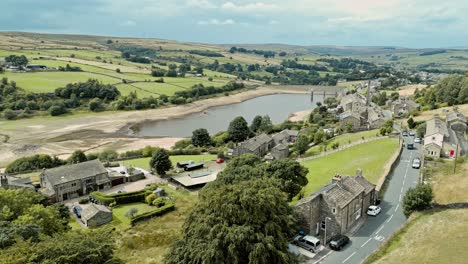 Aerial-footage-of-a-rural-industrial-village-with-old-mill-and-chimney-stack-surrounded-by-fields-and-farmland