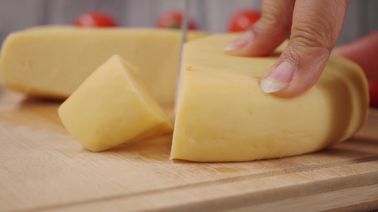 Personne coupant du fromage frais avec un couteau sur une planche à découper