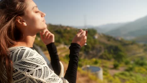 woman enjoying tea with a scenic view of mountains and a lake