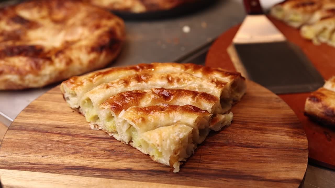 Rebanada de repostería salada dorada y hojaldrada sobre una tabla de madera