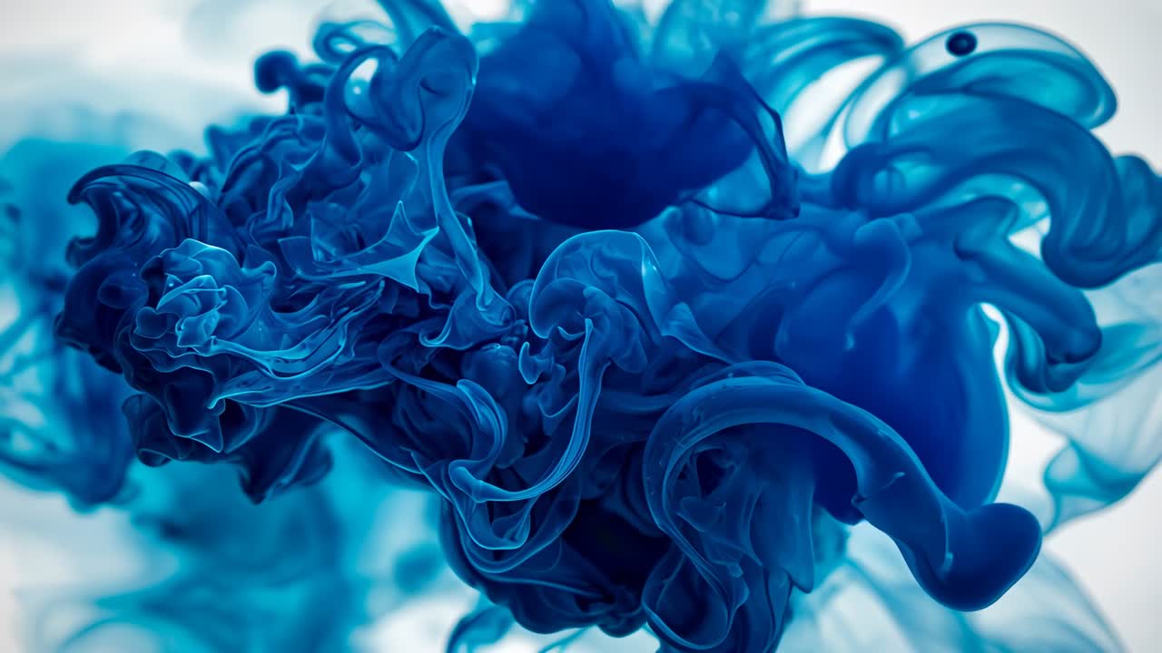 Injecting cobalt blue ink dye into water tank, swirling cloud expanding over bright white backdrop