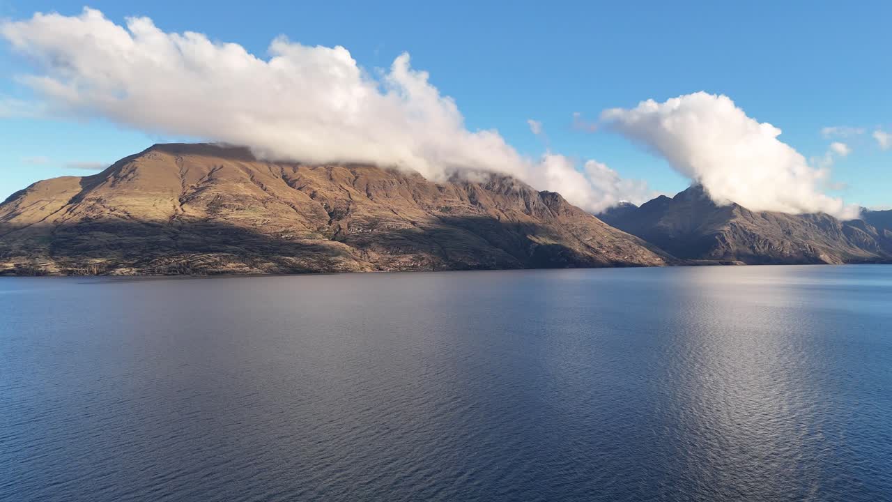 A tranquil scene of a lake and mountains under a clear blue sky, captured in Queenstown, New Zealand
