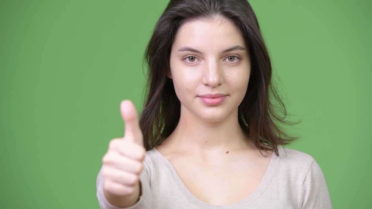 Young happy beautiful woman smiling while giving thumbs up