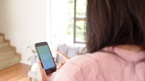 woman using smartphone app to control smart home lighting at home