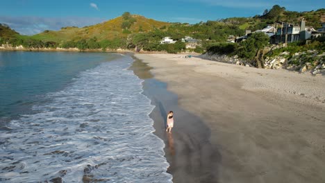 Hermosa-Mujer-Joven-Caminando-En-La-Playa-De-Hahei-Con-Olas-Salpicando