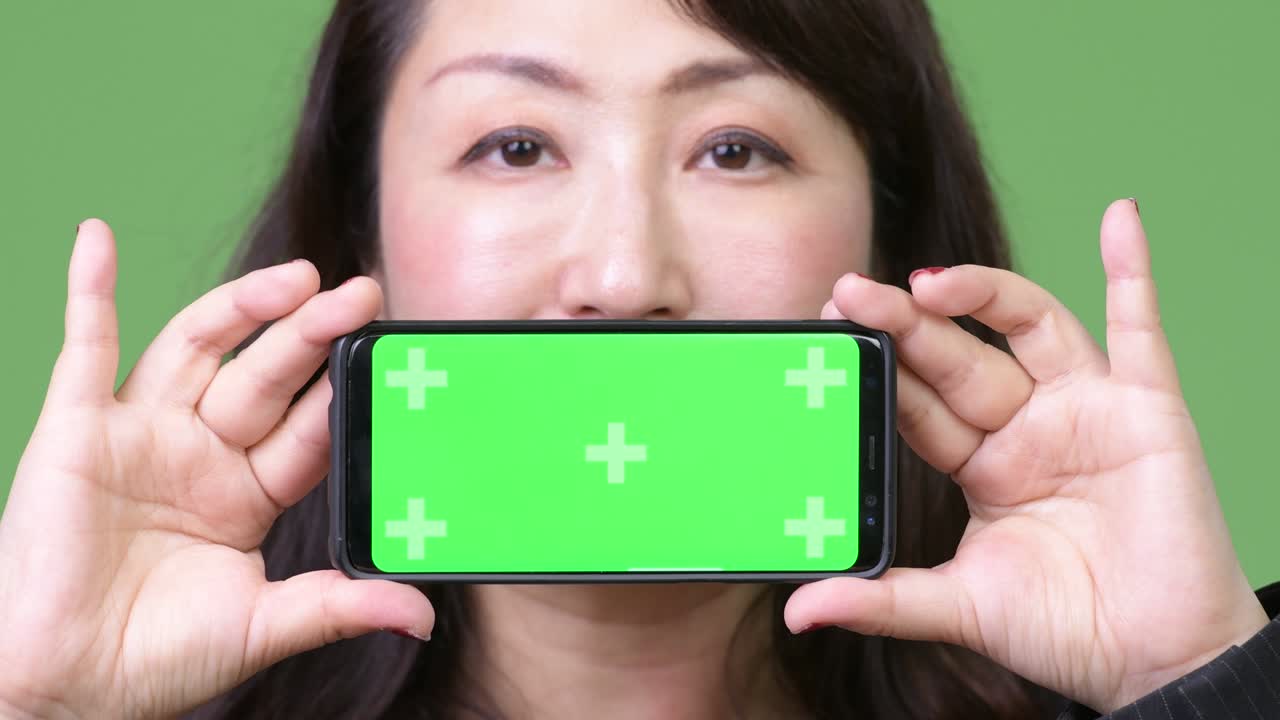 Mature beautiful Asian businesswoman showing phone