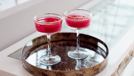 elegant red drinks in vintage glasses on decorative metallic tray