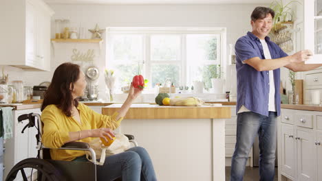 pareja asiática madura con esposa en silla de ruedas desempaquetando productos frescos en la cocina después de un viaje de compras - filmado en cámara lenta