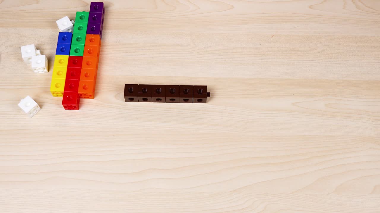 손은 테이블 위에 다채로운 연결 큐브를 조립하고 있습니다.