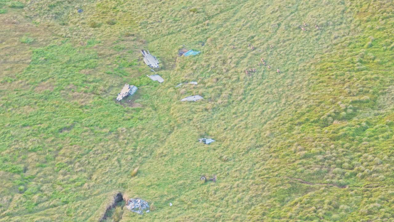 Top-down drone shot zooming in on the wreckage of a North American Sabre F.Mk 4 fighter jet, lying abandoned on a remote mountain slope in the Peak District, UK