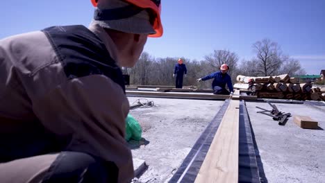 construction workers laying foundation for log house