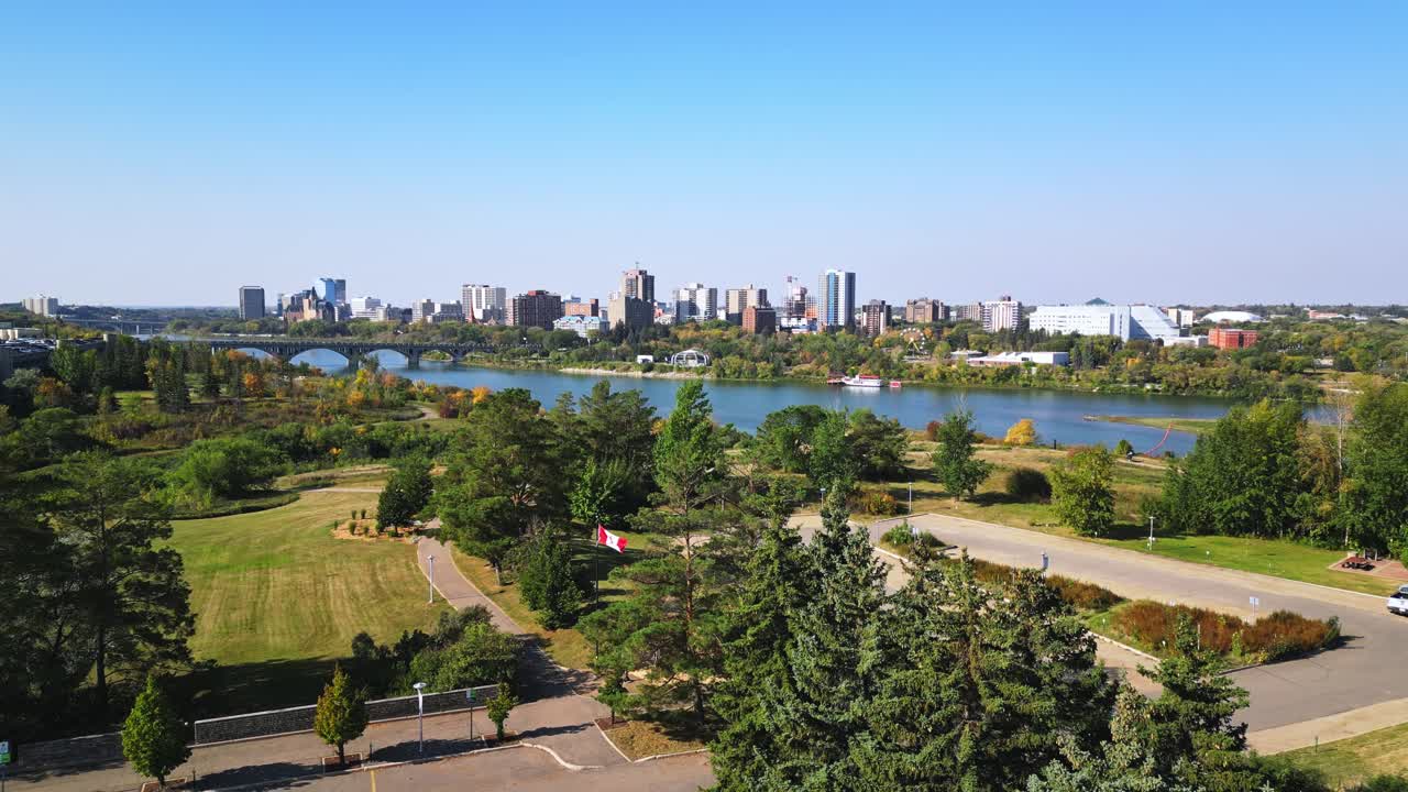 Daytime drone view of Saskatoon downtown, bridges, river, people, cars, flag