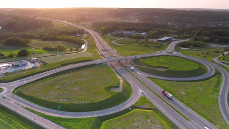 Toma-Aérea-De-Establecimiento-De-Tráfico-En-La-Intersección-De-La-Autopista-O-En-El-Cruce-De-Carreteras-Durante-La-Puesta-De-Sol-Dorada