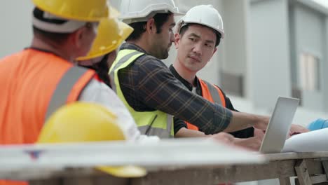 engineer meeting with team contractor and foreman, talking and explain housing construction model in laptop and blueprint. male and female worker working at construction site in real estate business.