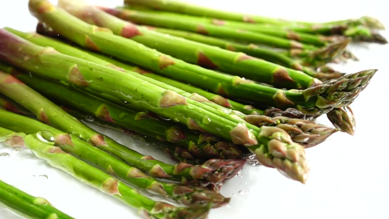 Verse groene asperges. Waterspatten. Vertraagde beweging.