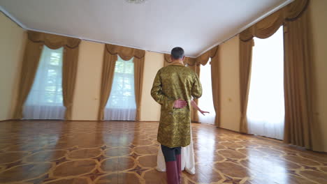 people in historic clothes performing old dance. a couple of adult people dancing in the big empty hall.