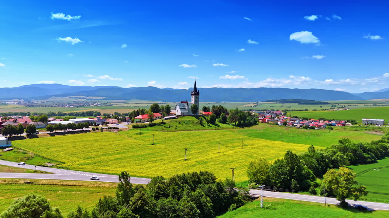 Church among scenic fields. Beautiful countryside showcases vibrant green fields, a charming church, and distant mountains under a clear blue sky