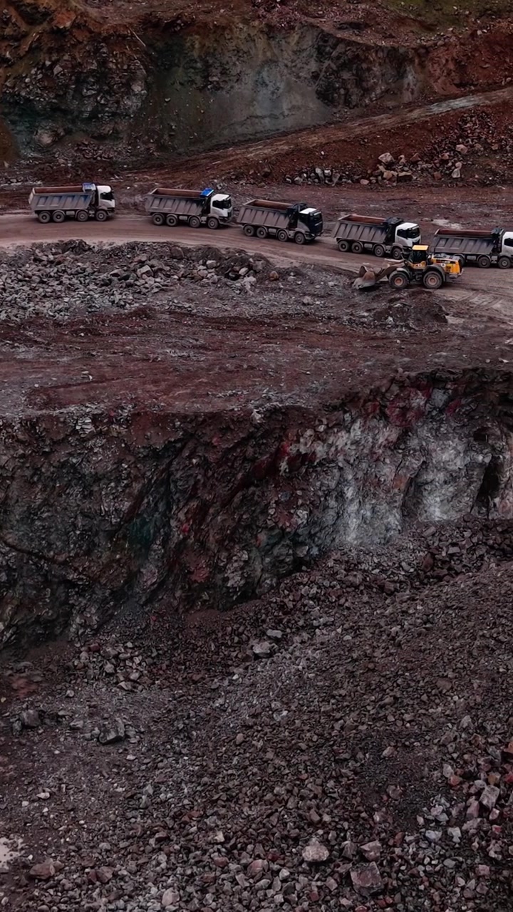 Dump Trucks and Excavator Working in an Open Pit Mine