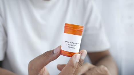 person holding a container of antiviral covid-19 medicine