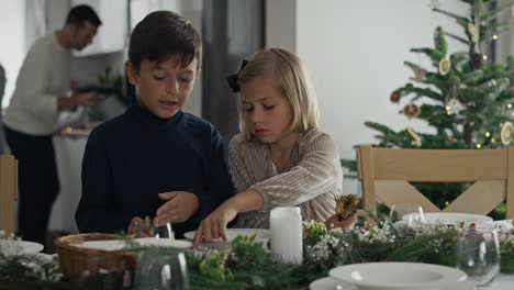 Two-caucasian-kids-preparing-table-for-Christmas-Eve.