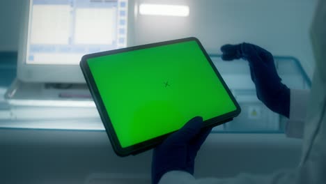 científico que utiliza una tableta con pantalla verde en un entorno de laboratorio