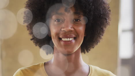 animation of portrait of happy african american businesswoman over light spots