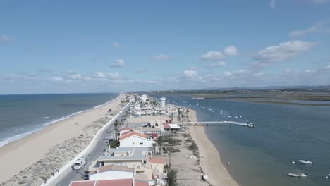 Vista-Aérea-De-Barcos-Navegando-Pacíficamente-En-El-Río-Mientras-La-Gente-Disfruta-De-La-Serena-Playa-Temprano-En-La-Mañana