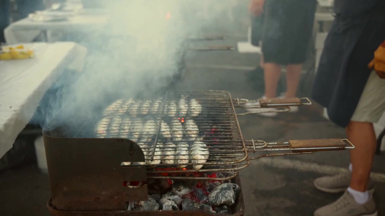 Maestro della griglia che cucina street food su un barbecue fumoso tra braci volanti, creando un delizioso aroma