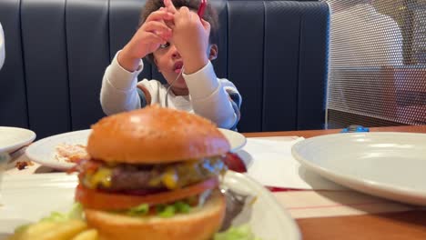 impatient two-year-old black baby, mix raced, wishing to taste his burguer