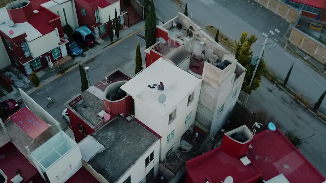 Orbital shot of a drone operator on the roof of a house at sunset in a residential area in the metropolitan zone of Mexico City