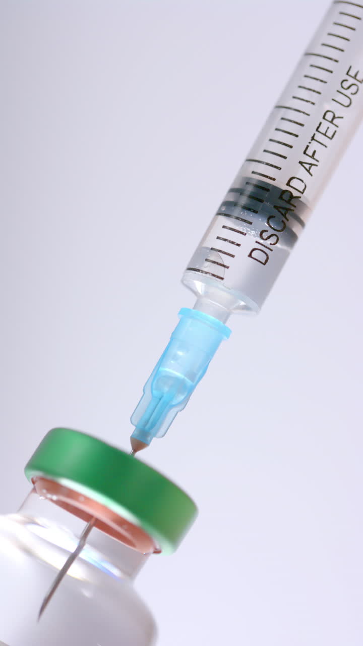 Vertical video of insulin vial and syringe on white background, slow motion
