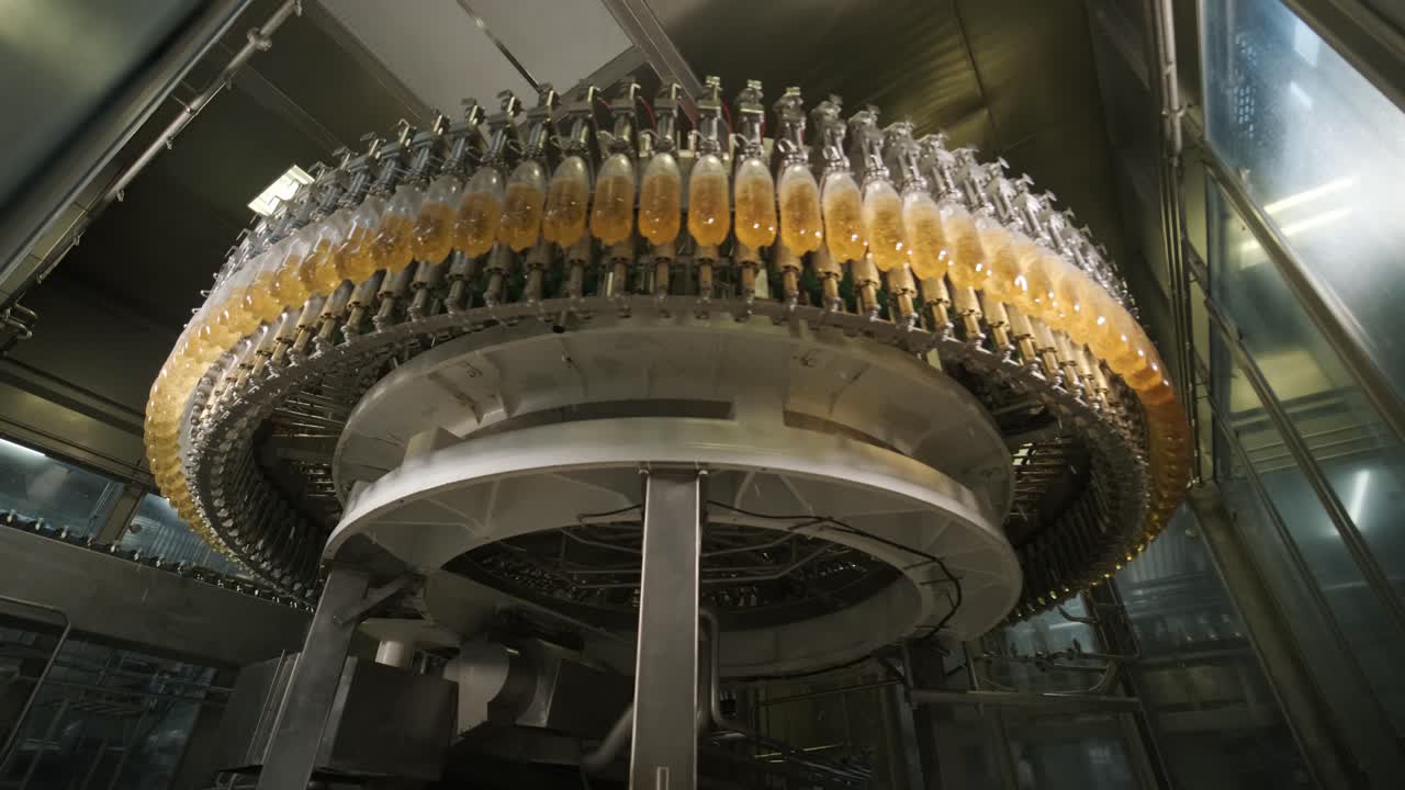 Automatic filling machine pours water into plastic PET bottles at modern beverage plant
