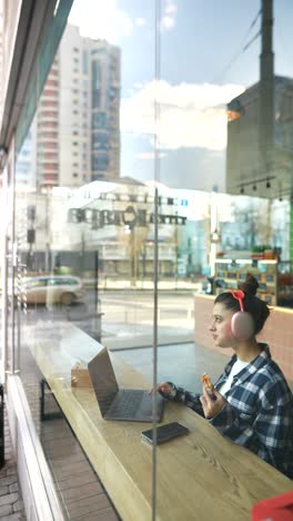 young woman working and eating pizza at a cafe