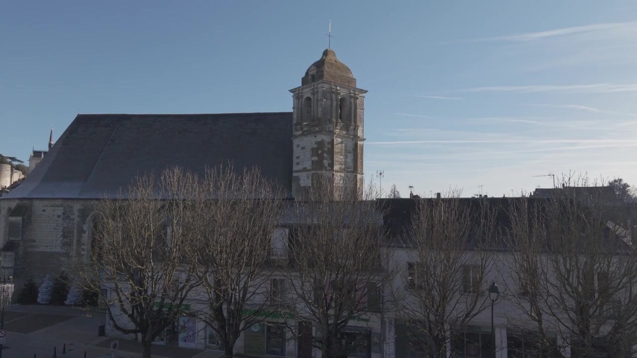Uma vista aérea mostra uma torre de igreja de pedra com um relógio elevando-se acima dos telhados de ardósia de uma vila do Vale do Loire