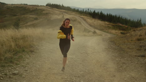 Chica-Corriendo-Rápido-Por-Un-Camino-Sucio.-Mujer-Deportiva-Sonriente-Entrenando-En-Las-Montañas