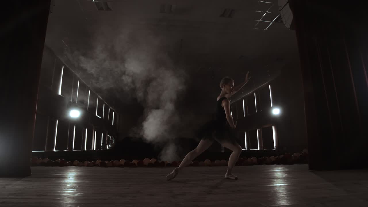 movimiento lento: ballet prima en el escenario ensayando la actuación en la luz oscura de la contra. las luces de la sala.
