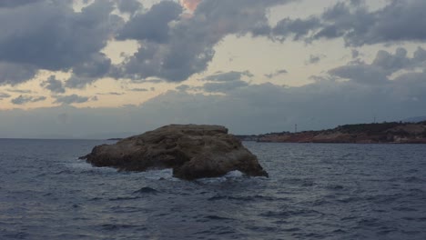 Aerial---Small-skerry-in-Vouliagmeni,-Greece-at-sunset