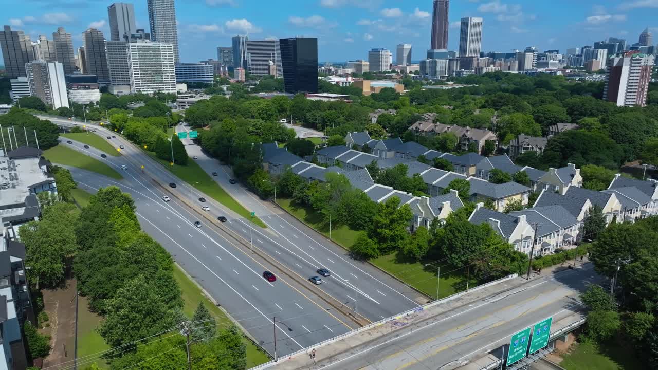 Modern communist houses near downtown Atlanta. Aerial wide shot. Traffic on main highway road. Skyline with skyscrapers in distance. Sunny day in summer.
